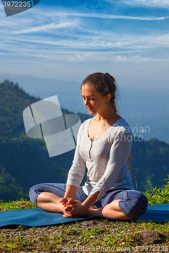 Image of Sporty fit woman practices yoga asana Baddha Konasana outdoors