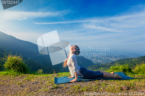 Image of Woman practices yoga asana Urdhva Mukha Svanasana outdoors