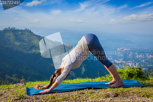 Image of Young sporty fit woman doing yoga oudoors in mountains