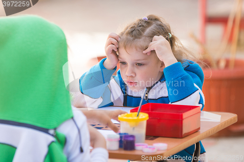 Image of Two girls paint in the yard, one of them looked at the other pattern