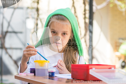 Image of Girl draws paints in the yard in the spring sunny day and looked into the frame