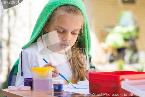 Image of Girl draws paints in the yard in the spring sunny day