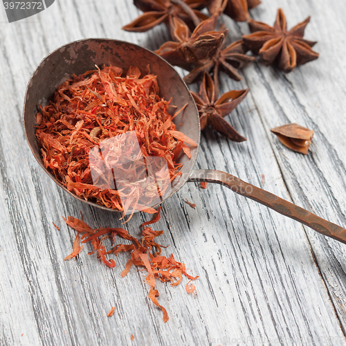 Image of saffron in spoon with anise on wooden background
