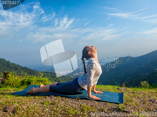 Image of Woman practices yoga asana Urdhva Mukha Svanasana outdoors