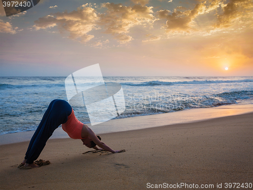 Image of Woman doing yoga Surya Namaskar oudoors at tropical beach