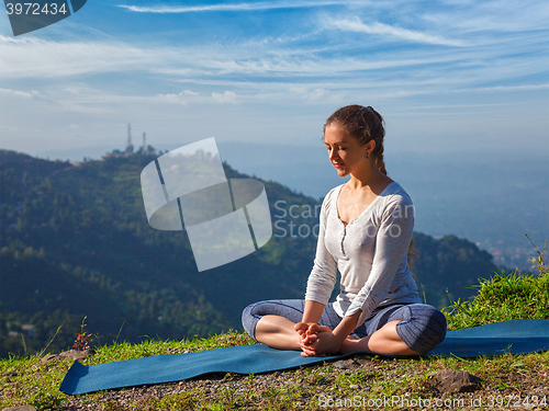 Image of Sporty fit woman practices yoga asana Baddha Konasana outdoors