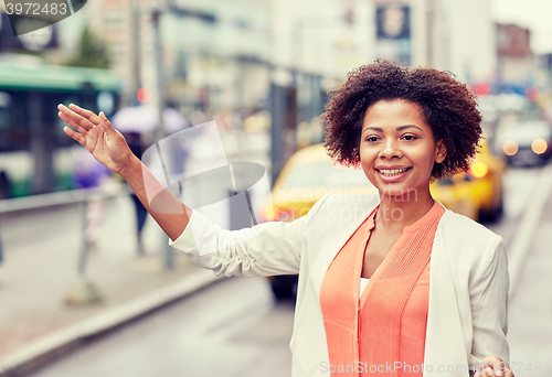 Image of happy african woman catching taxi