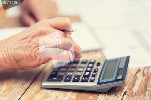 Image of close up of senior woman counting with calculator