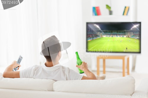Image of man watching soccer game on tv and drinking beer