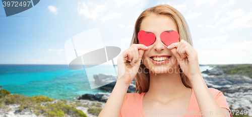 Image of happy young woman with red heart shapes on eyes