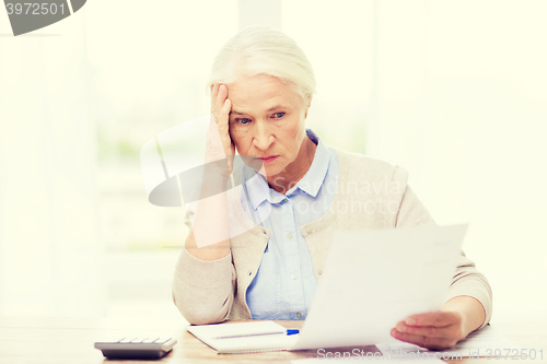 Image of senior woman with papers and calculator at home