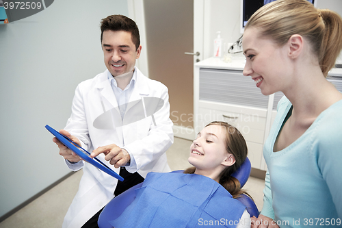 Image of dentist showing tablet pc to girl and her mother