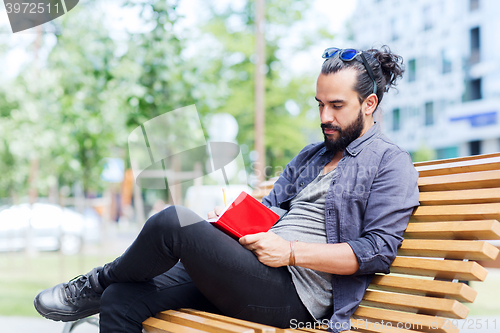 Image of man with notebook or diary writing on city street