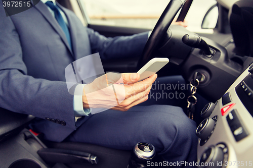 Image of close up of man with smartphone driving car