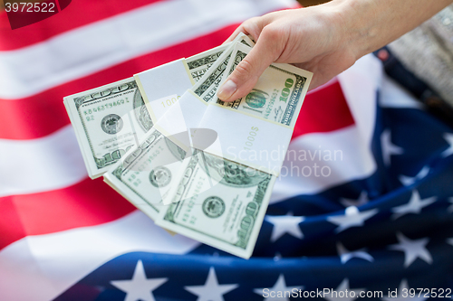 Image of close up of hand with money over american flag