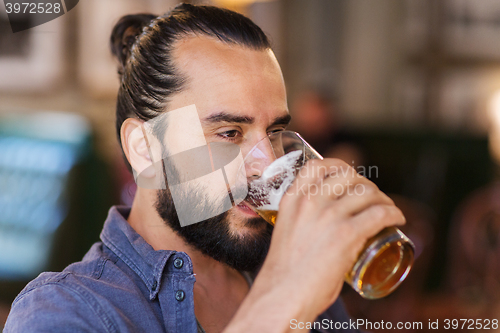 Image of happy man drinking beer at bar or pub