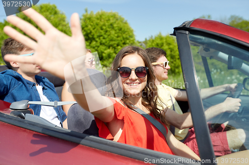 Image of happy friends driving in cabriolet car at country