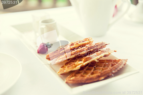 Image of close up of waffles on plate at breakfast table 