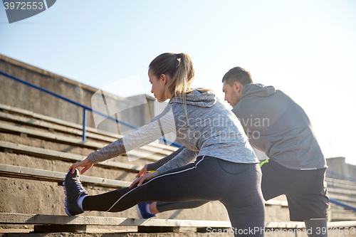 Image of couple stretching leg on stands of stadium