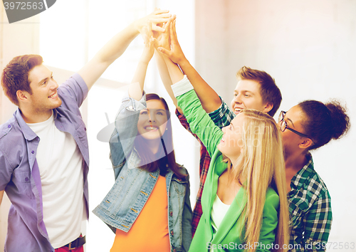 Image of happy students giving high five at school