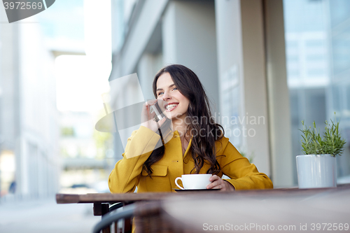 Image of happy woman calling on smartphone at city cafe