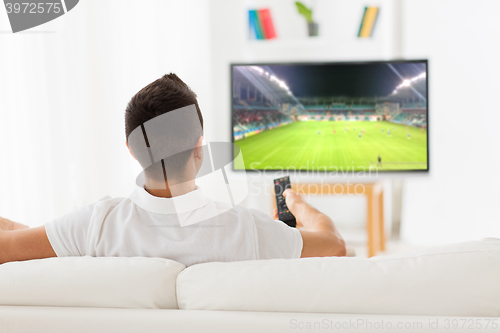 Image of man watching football or soccer game on tv at home