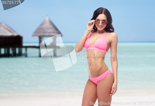 Image of happy woman in sunglasses and bikini on beach