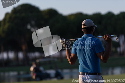 Image of golfer from back at course looking to hole in distance