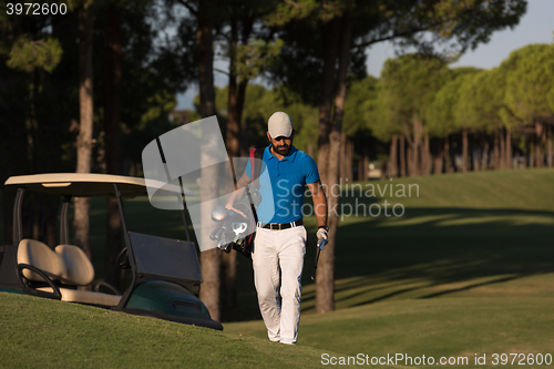 Image of golfer  walking and carrying golf  bag