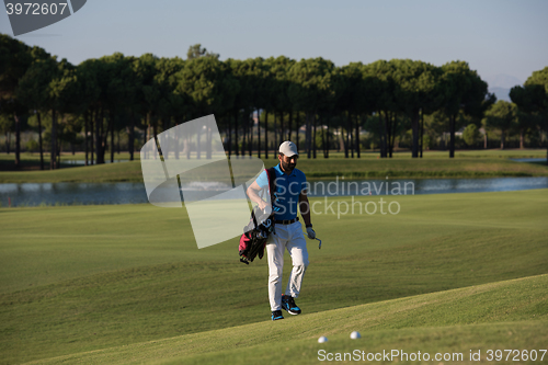 Image of golfer  walking and carrying bag