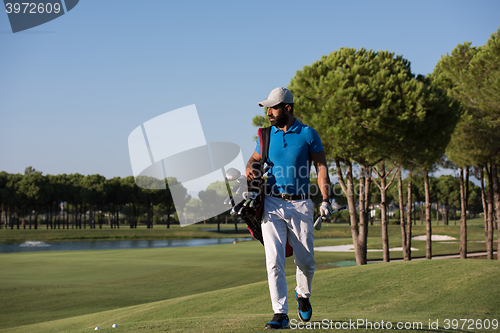 Image of golfer  walking and carrying bag