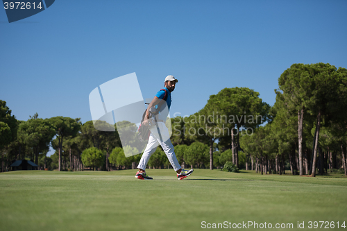 Image of golf player walking and carrying bag