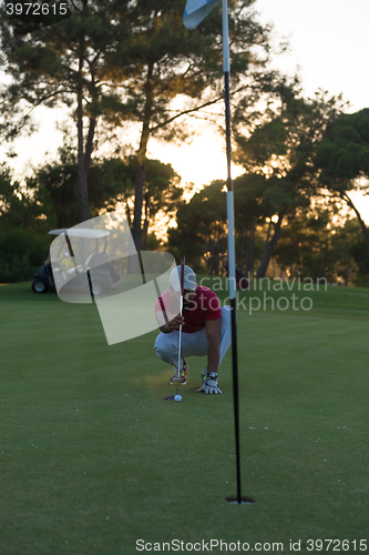 Image of golf player aiming perfect  shot on beautiful sunset