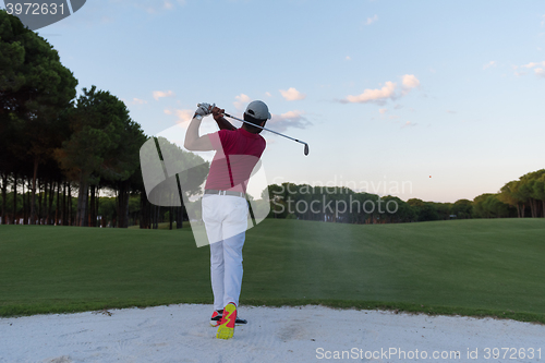 Image of golfer hitting a sand bunker shot on sunset