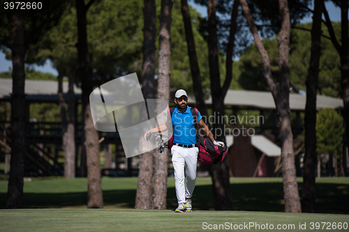 Image of golf player walking and carrying bag