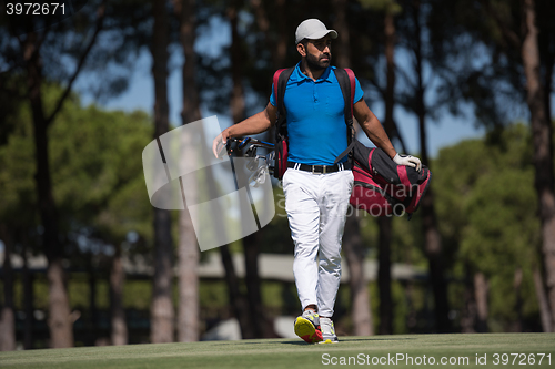 Image of golf player walking and carrying bag