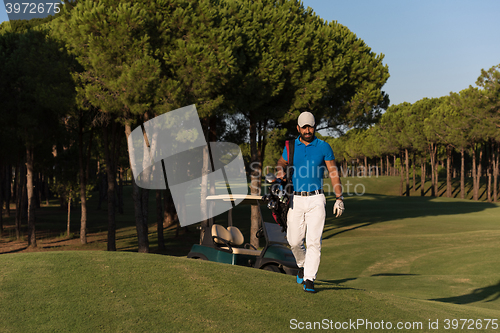 Image of golfer  walking and carrying golf  bag