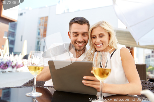 Image of happy couple with tablet pc at restaurant terrace