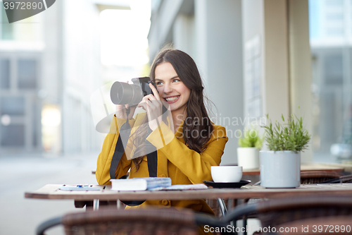 Image of happy tourist woman with camera at city cafe