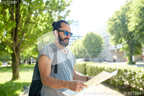 Image of man traveling with backpack and map in city