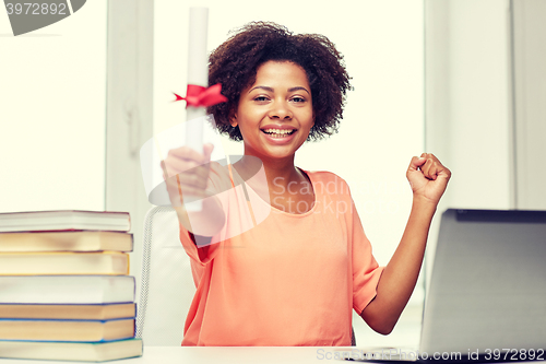 Image of happy african woman with laptop, books and diploma