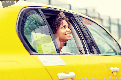 Image of happy african american woman driving in taxi