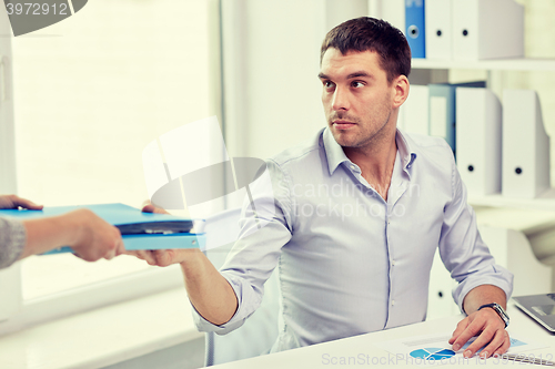 Image of businessman taking folder from secretary in office