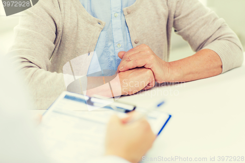 Image of close up of senior woman and doctor with clipboard