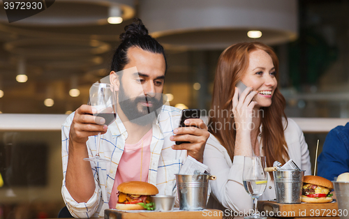 Image of happy friends with smartphones at restaurant