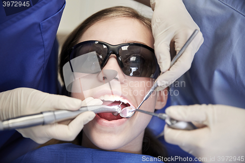 Image of female dentists treating patient girl teeth