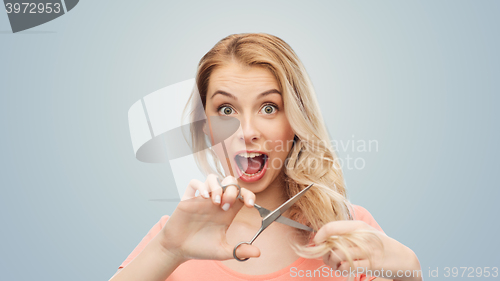 Image of woman with scissors cutting ends of her hair