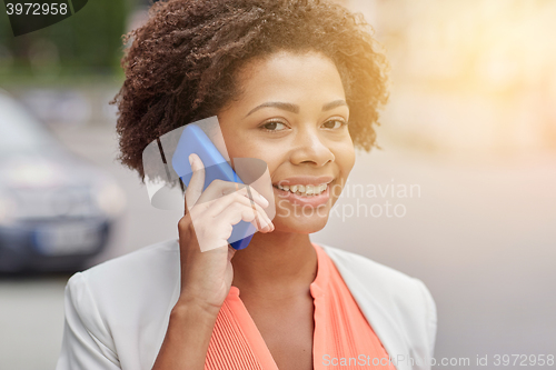 Image of happy african businesswoman calling on smartphone