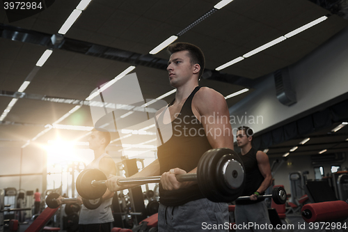 Image of group of men flexing muscles with barbell in gym