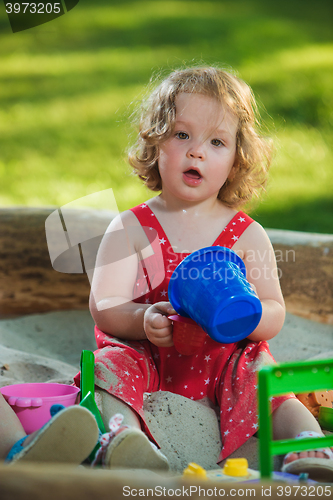 Image of The little baby girl playing toys in sand